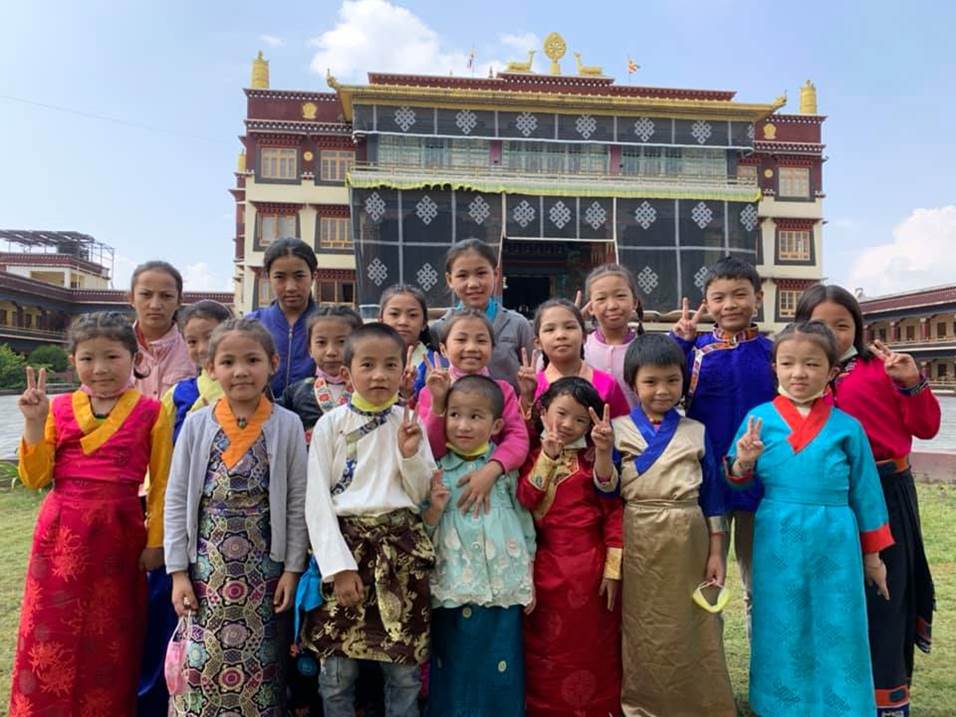 A group of people posing for a photo in front of a building

Description automatically generated