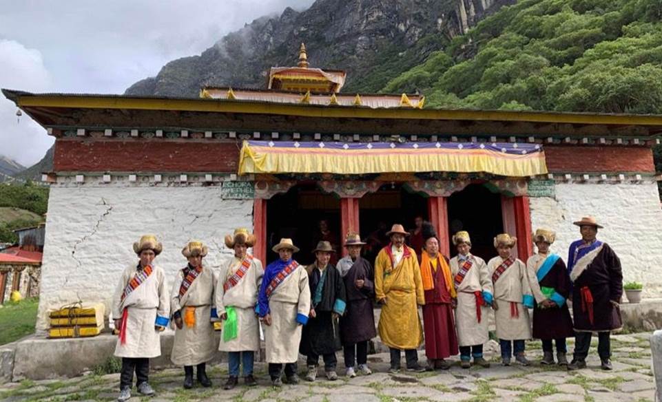 A group of people standing outside a building with a mountain in the background

Description automatically generated with medium confidence